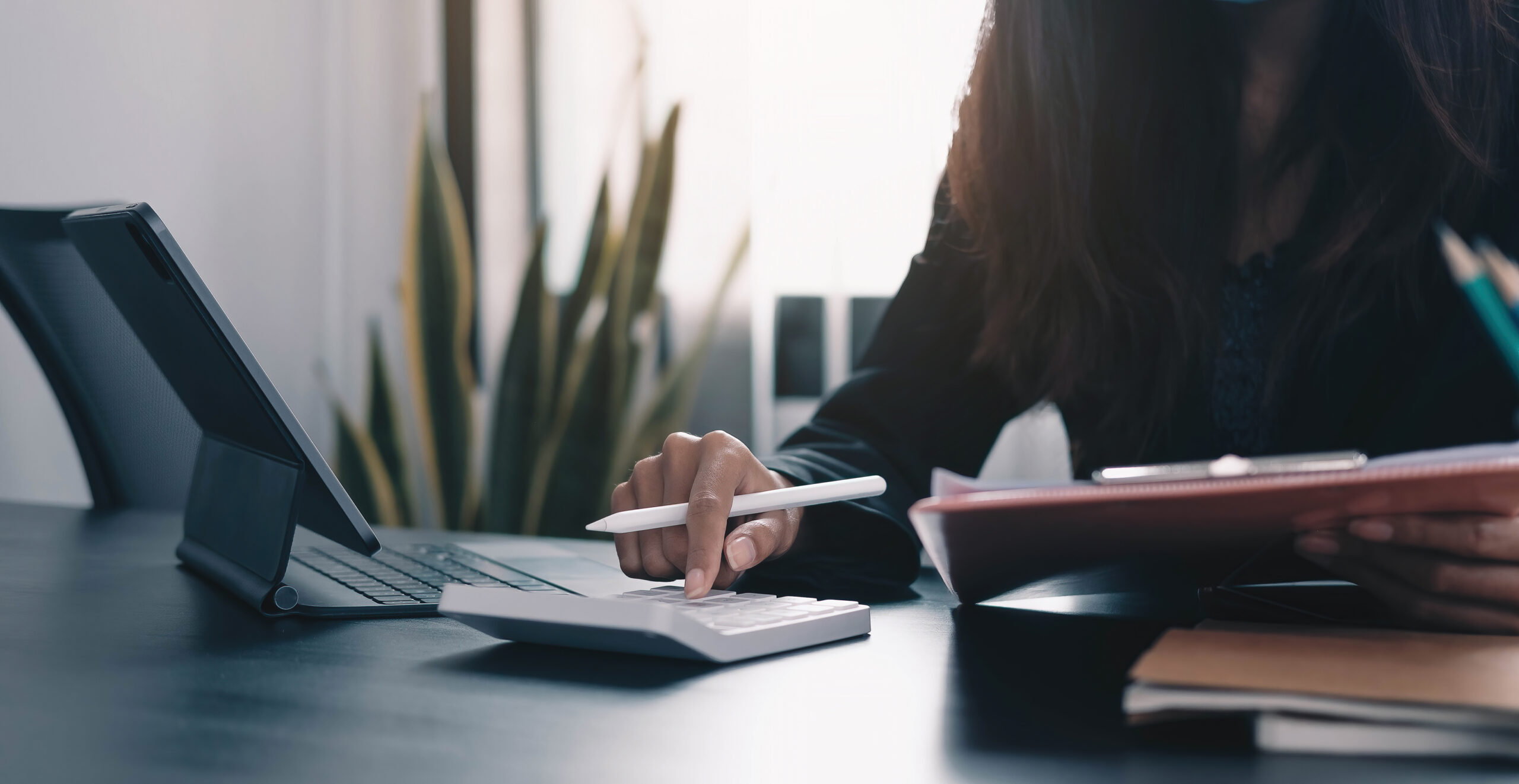 Close up Business woman using calculator and laptop for do math finance on wooden desk in office and business working background, tax, accounting, statistics and analytic research concept